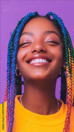 Portrait of a young woman with colorful hair extensions smiling brightly.