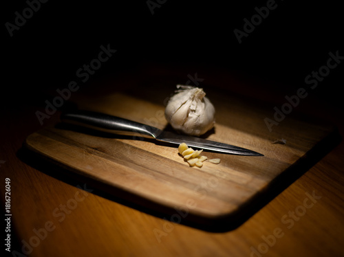 Close-up of a bulb of garlic on a wooden chopping board with a sliced clove of garlic