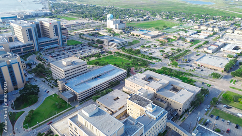 High-rises medical buildings and palm-lined streets toward port facilities in Galveston, Texas, capturing blend of domestic life, institutional presence, and industrial coastal infrastructure