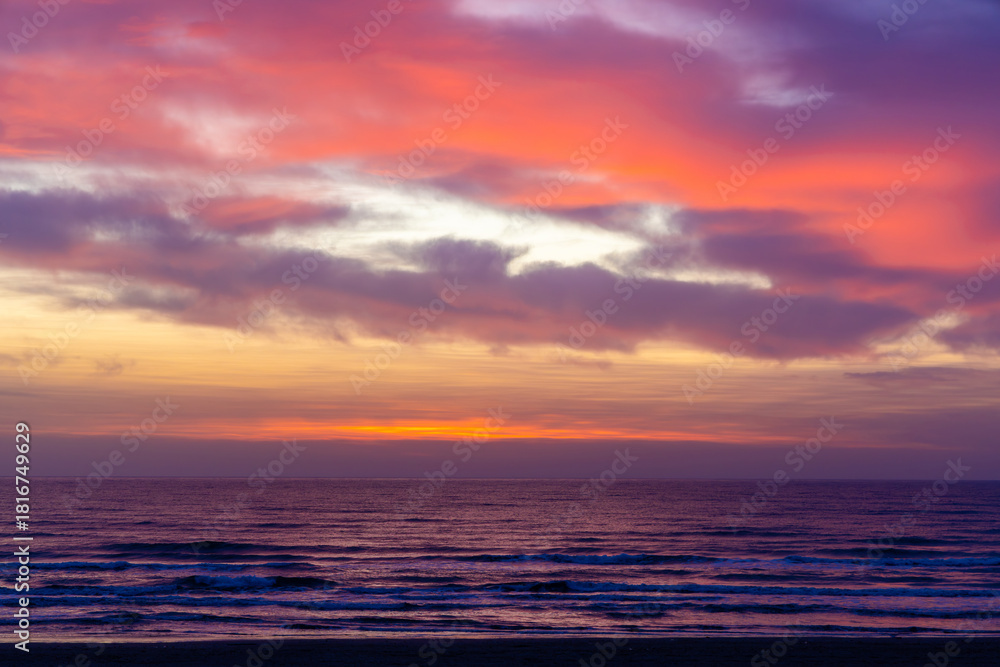 Fototapeta premium Landscape with a beautiful sunset over the ocean with vibrant colors, including deep reds, oranges, and purples, with dramatic clouds