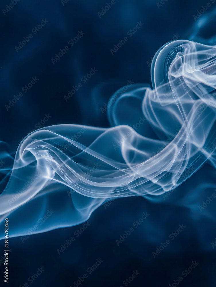 Fototapeta premium Delicate wisps of white smoke swirling gracefully against a deep blue background, creating an ethereal and mesmerizing abstract pattern in motion