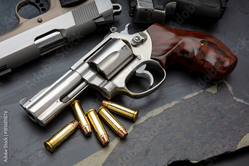 Foto Revolver handgun and bullets on black stone background