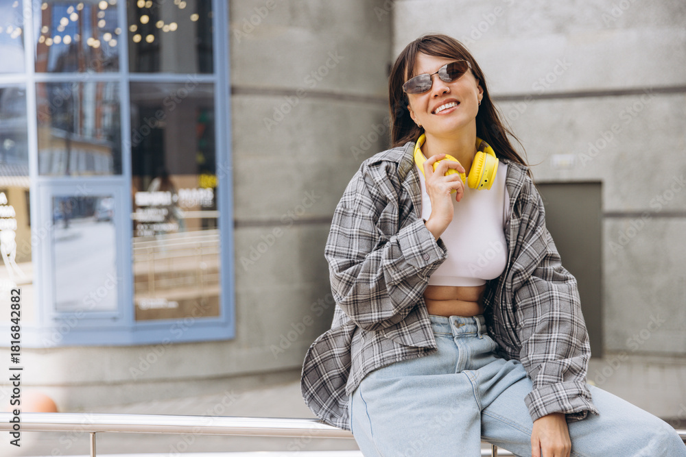 Fototapeta premium Young woman smiling with headphones in urban setting