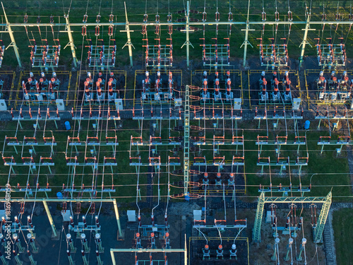 Aerial view of high-voltage electrical substation switchyard, energy infrastructure, complex grid infrastructure with insulators and lines.