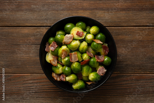 Top view of Brussels sprouts roasted with bacon in bowl wooden surface