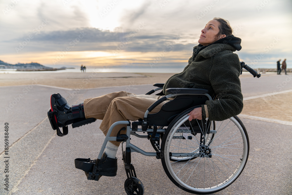 Obraz premium Young disabled woman in a wheelchair enjoying the landscape and the sea - Travel adventure