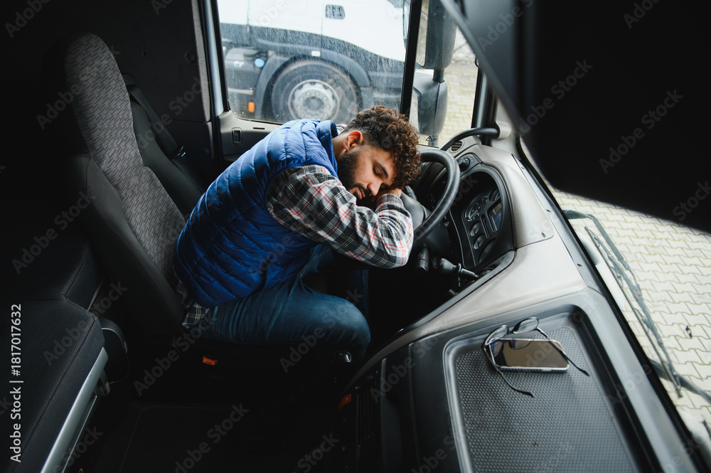 Obraz premium Truck driver sleeping at steering wheel taking a much needed rest