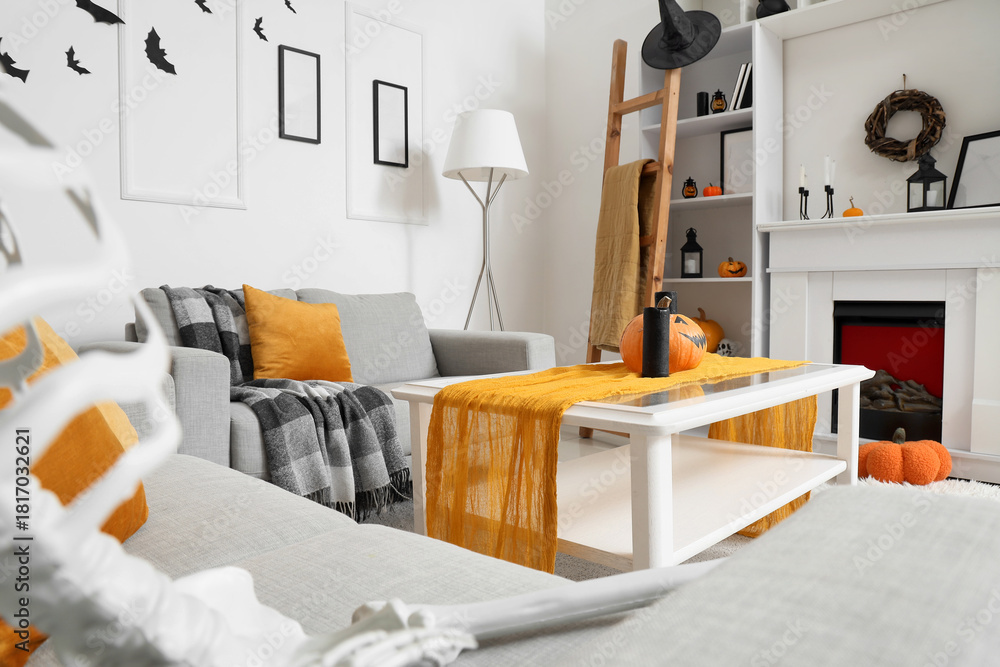 Fototapeta premium Interior of light living room decorated for Halloween with sofas, fireplace and shelf unit