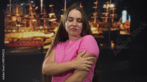 Wallpaper Mural Woman holding upper arm in museum gallery near ship exhibit with eyes closed and slight grimace; introspection discomfort. Torontodigital.ca