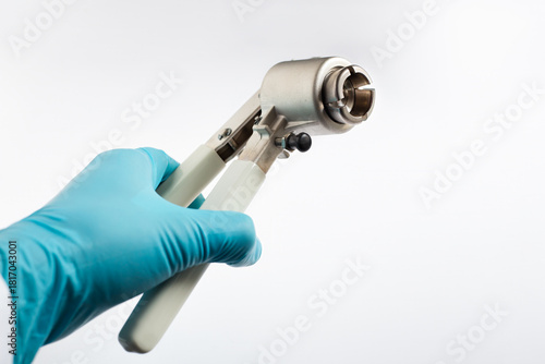 Photos A scientist's hand holds a manual vial crimper used to seal aluminum caps onto glass autosampler vials in the laboratory