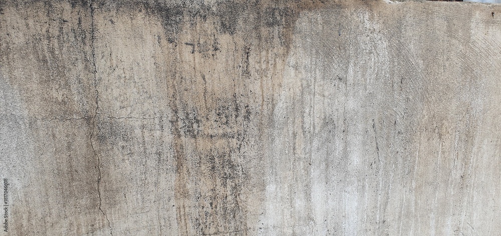 Fototapeta premium The view of an old weathered concrete wall featuring cracks and natural aging patterns. Ideal for use as a textured background in design, architecture references, or artistic visual projects.