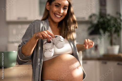 Pregnant Woman Holding Baby Shoes