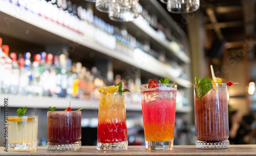 Schilderij op canvas Five vibrant, colorful cocktails lined up on a sleek bar counter, each garnished with fresh fruit, mint, and citrus twists