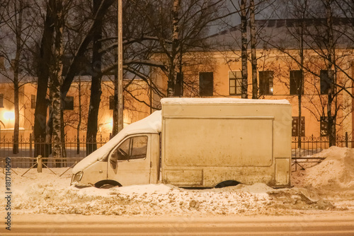 a small truck with a van parked on the side of the road, covered in snow