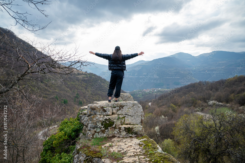 Obraz premium Young woman standing on a rock in the autumn cloudy mountain