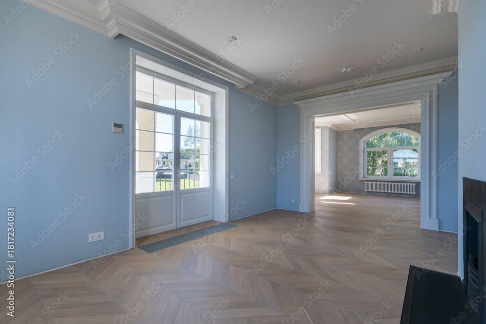 Obraz premium This modern interior features a bright blue room filled with natural light from large windows. The open layout displays beautiful wooden flooring, inviting a fresh atmosphere