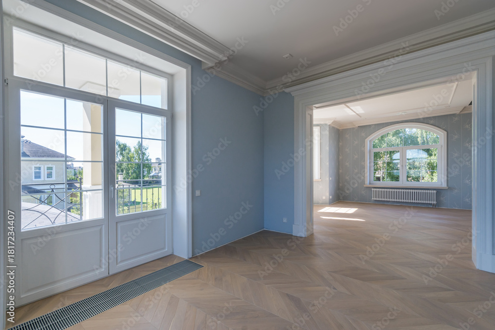 Obraz premium Bright and airy interior showcases renovated rooms with large windows allowing natural light. Smooth wooden flooring and elegant walls create a welcoming atmosphere in the home