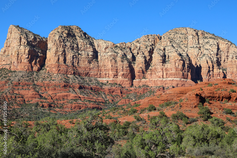 Naklejka premium Layered Red and White Rock Wall in Rugged Desert Terrain