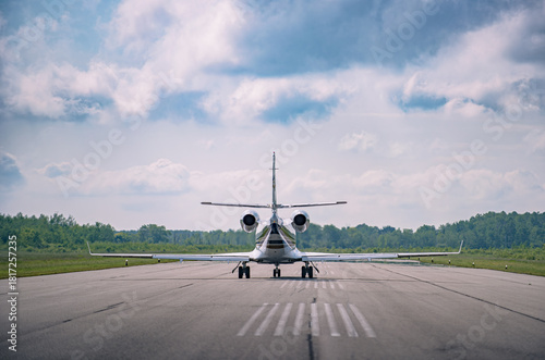 Seen from behind a small corporate jet taxing to the end of the runway at a small regional airport, Ontario Canada. Selective focus to soften the background.