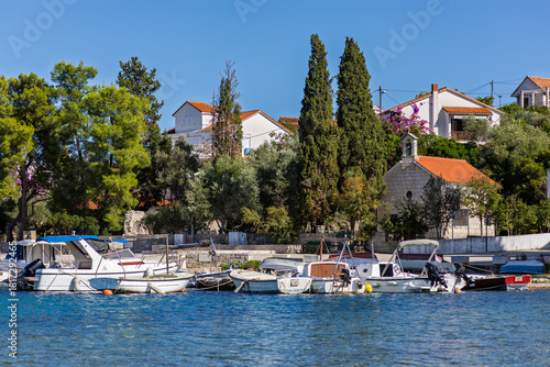 Serene Coastal Village Harbor With Boats and Lush Trees Under Bright Blue Sky, Necujam, Croatia