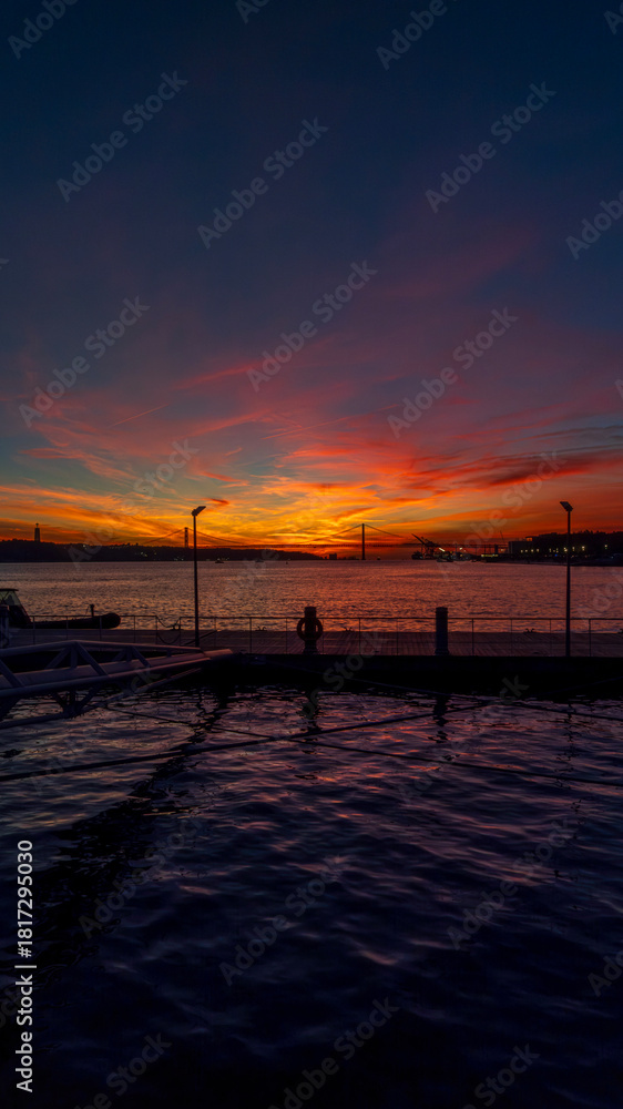 Naklejka premium Sunset seen from Cais das Colunas in Lisbon with a view of the 25 de Abril Bridge