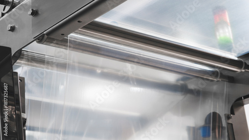 Automatic polyethylene plastic bag production machine with lighting effect. Close-up of the roller of the plastic bag production machine in the light blue scene. product packaging concept