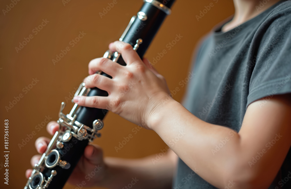 Fototapeta premium Childrens hands play clarinet in music studio. Young person practices woodwind instrument, learns musical notes and melody. Child develops finger technique for band class.