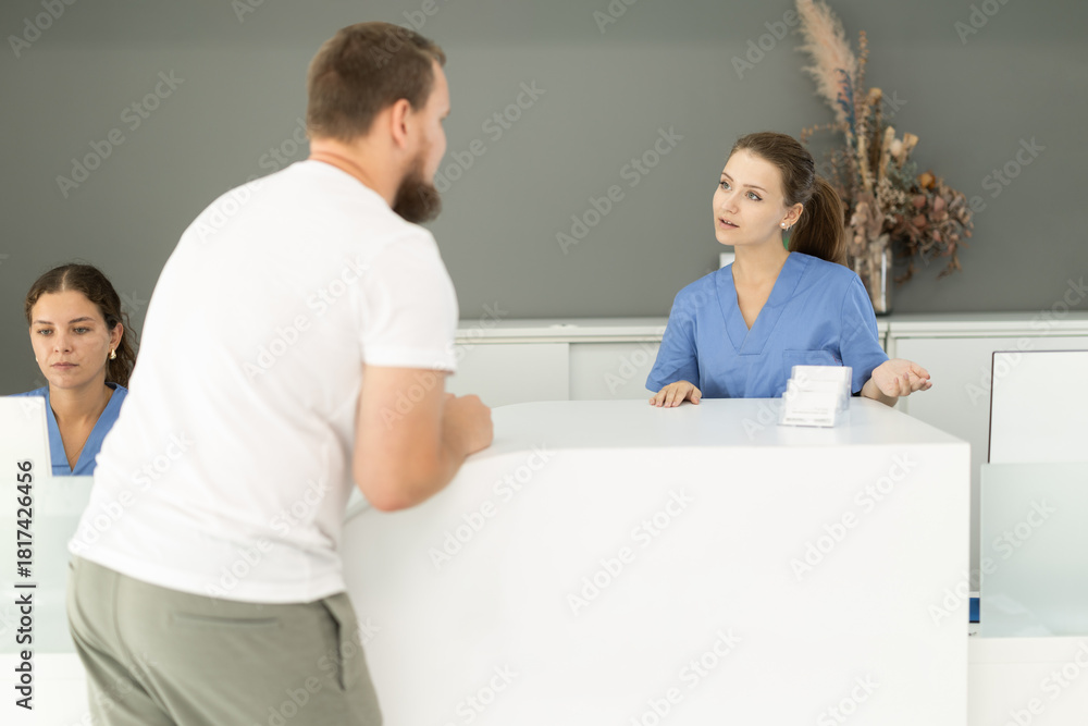 Obraz premium Dental clinic administrator talks to patients at the reception desk