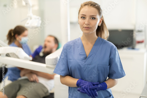 Woman dental assistant invites clients for professional dental hygiene and whitening. Qualified treatment in the dental studio