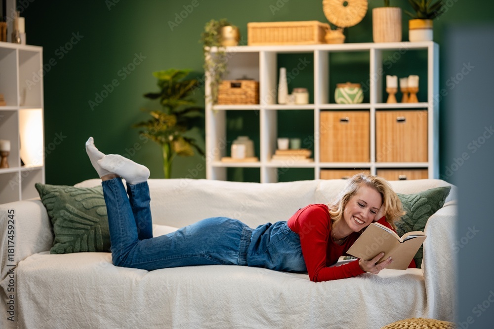 Obraz premium Young woman enjoying reading book on sofa