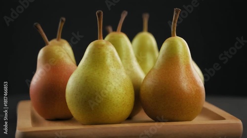 Fresh pears arranged on a wooden tray. These succulent fruits are captured in a close-up shot, highlighting their natural textures and colors