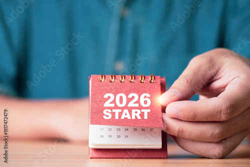 Hand flipping a calendar to reveal 2026 START symbolizing new beginnings future planning goal setting motivation and business strategy for corporate projects personal development and creative content.