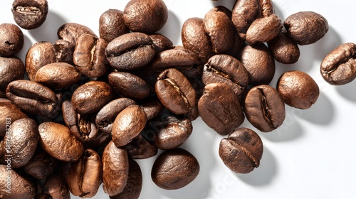 Dark roasted coffee beans scattered across a bright white surface with dramatic lighting