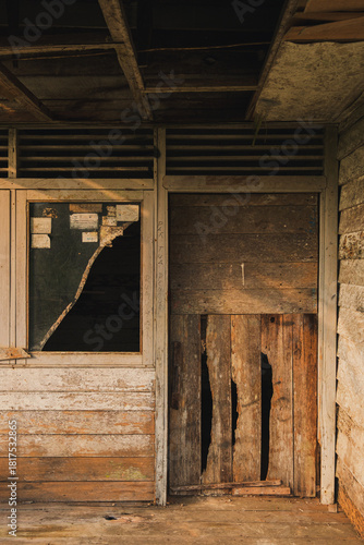Broken Window and Decaying Doorway of Abandoned Wooden Building