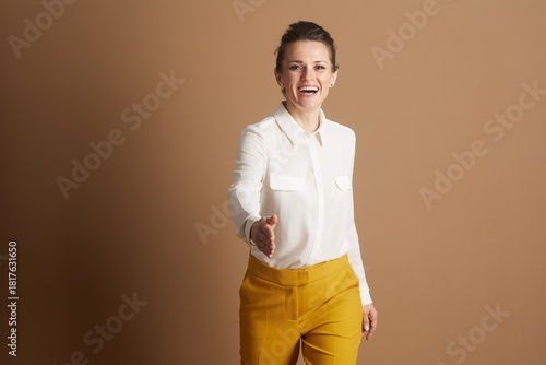 A smiling businesswoman extends her hand for a warm handshake, symbolizing partnership, greeting, and strong professional connections in corporate or customer service roles.