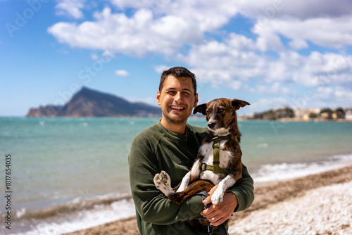 Man holding a brown dog on his lap while smiling at the camera