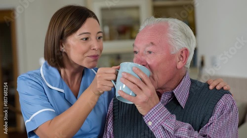 Young caregiver smiling offering hot tea to elderly man cozy home setting, warm compassionate moment shared. smiling caregiver elderly man cup home