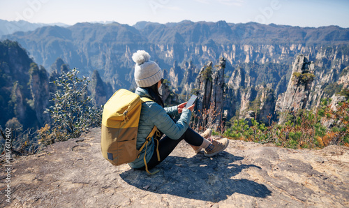 Female  tourist taking selfie with smart phone hiking in mountains