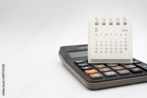 Desk calendar for February 2026 on white background. Calendar concept with 2026 FEB. Calculator and forecast for finances in 2026. Money, Budget, tax, investment and financial.