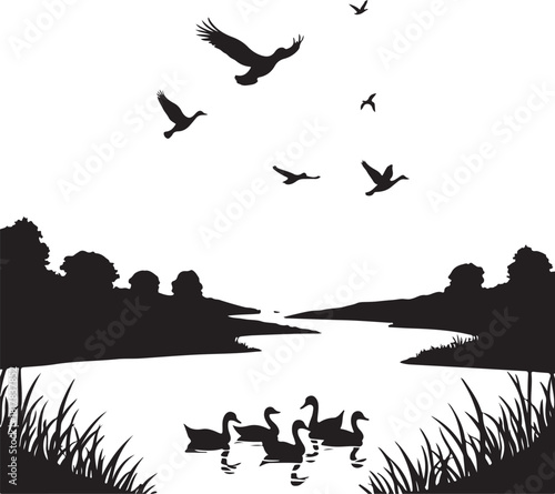 Black silhouette of birds flying over a lake with ducks