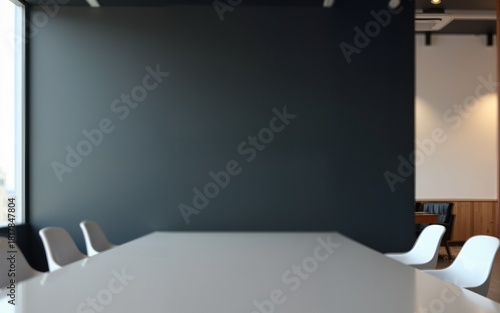 Blank dark wall mockup in modern office interior with blurred meeting room and white chairs in background with copyspace for branding or signage. High quality