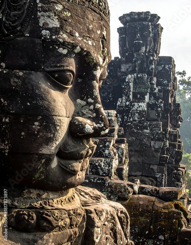 Close-up of a carved stone face with details, other structure blurred in background, natural lighting