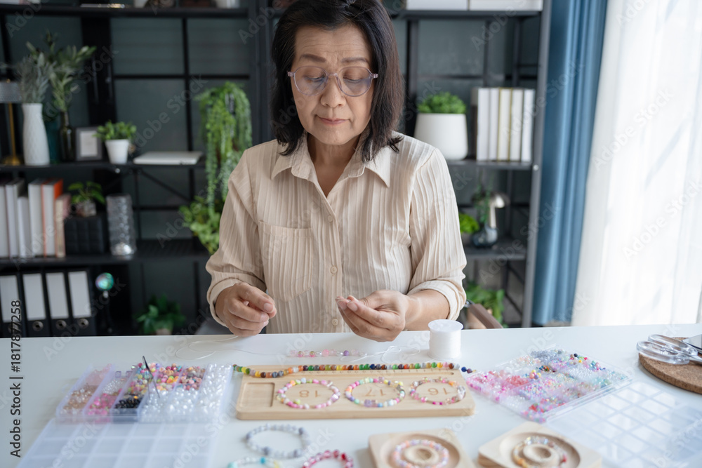 Fototapeta premium Senior mature older asian woman Art hobby handmade making beads jewellery accessories handcraft hobby
