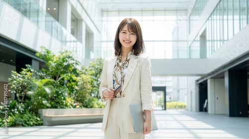 ノートパソコンを持つカジュアルスーツを着た笑顔の女性