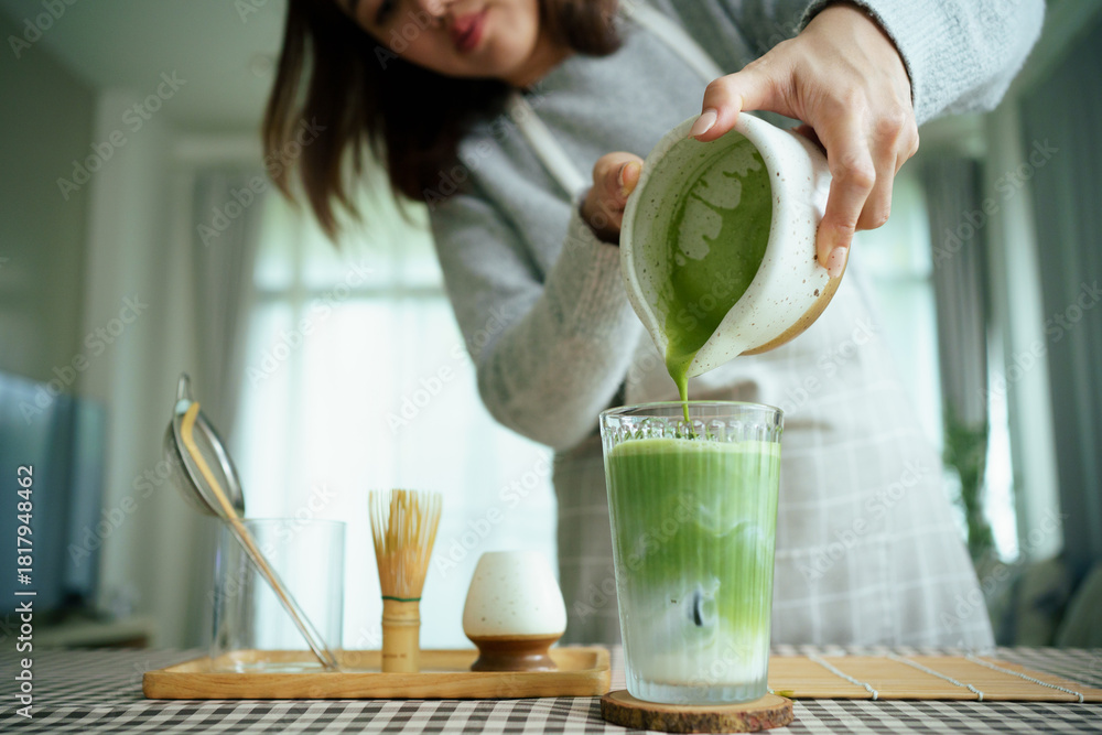 Naklejka premium Barista pouring matcha into iced milk to make a layered matcha latte.
