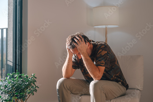 Canvastavla Depressed man leaning forward with hands on his head, struggling with anxiety or bad news in a bright, quiet living room