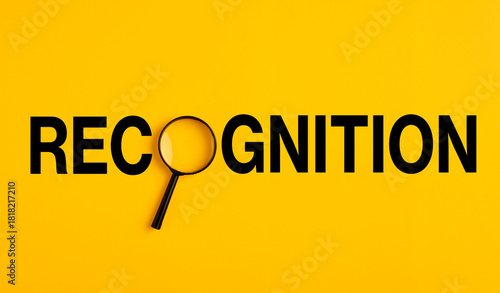 Magnifying glass exploring recognition word on yellow background