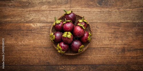 Mangosteen fruit with purple skin and green sepal on wooden surface, emphasizing tropical fruit harvesting practices