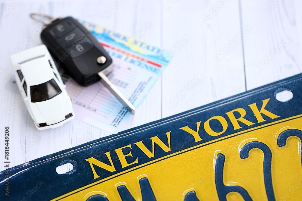 Obraz premium Remote control car keys on New York license plate with driver license. Concept of driving in New York. Reaching a driving permit