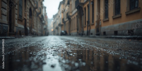 Blurred street scene with rain-soaked pavement and historic architecture, suitable for background in editorial layouts